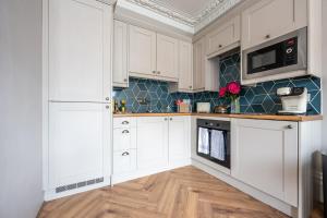 uma cozinha com armários brancos e azulejos azuis em Luxury Central Retreat with Off Road Parking em Southampton
