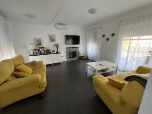 a living room with two couches and a table at Chalet con piscina privada, parking y zona BBQ in Isla Canela