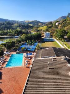 a pool with chairs and umbrellas in a resort at Hotel Cavalinho Branco - Apartamento 136 in Águas de Lindoia
