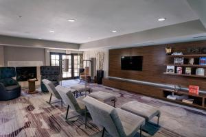 a living room with chairs and a flat screen tv at Courtyard by Marriott Henderson - Green Valley - Las Vegas in Las Vegas