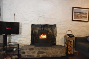 a fireplace in a living room with a fire in it at Seal Cottage in Portnahaven