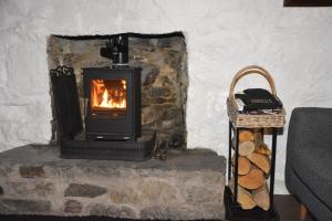 a stone fireplace with a stove in a room at Seal Cottage in Portnahaven