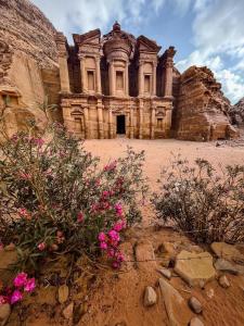 an old building with pink flowers in front of it at Indiana Jones Cave in ‘Ayn Amūn