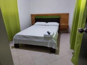 sypialnia z łóżkiem i zieloną zasłoną w obiekcie Apartahotel Avenida Las Margaritas w mieście Apartadó