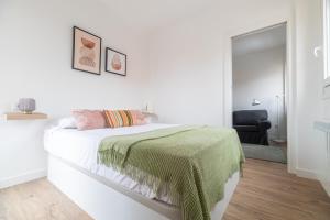 - une chambre blanche avec un lit et une couverture verte dans l'établissement La Terracita, à Vigo