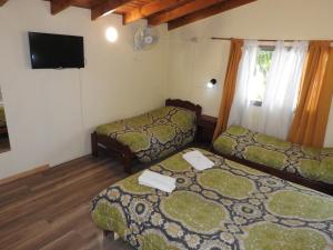 a room with two beds and a flat screen tv at Los Girasoles team family in El Bolsón