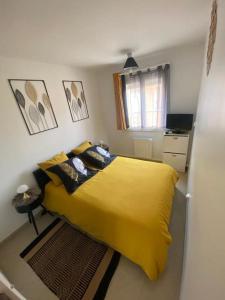 a bedroom with a yellow bed and a refrigerator at Fleur d'Or Proche ŔER C Evry in Brétigny-sur-Orge