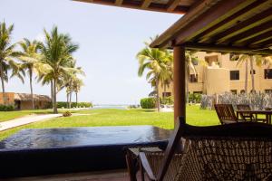 a patio with a table and chairs and palm trees at Condo BEACH FRONT PLAYA BLANCA GARDEN in Zihuatanejo