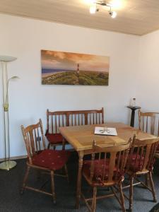 a dining room table with chairs and a painting on the wall at Ferienhaus Sonnendeck in Dornum