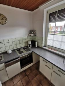 a kitchen with a stove and a clock on the wall at Ferienhaus Sonnendeck in Dornum