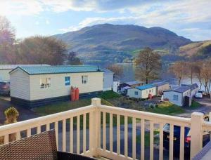 a balcony with a view of a town and mountains at Loch Earn Holiday Home in Saint Fillans