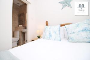 um quarto com uma cama branca e almofadas azuis em Cosy Apartment In The Heart Of Uplands - Swansea - Prime Location - By EKLIVING LUXE em Swansea