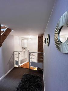 einen Flur mit einer Treppe mit einem Spiegel an der Wand in der Unterkunft Maison au calme avec Jardin proche Paris-Bercy in Charenton-le-Pont