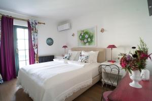a bedroom with a white bed and a vase of flowers at Nomad Rooms in Mostar