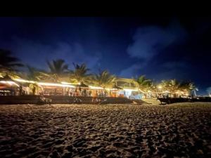 a beach at night with a building and palm trees at THE GILPINs in Lekki