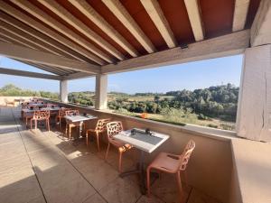une terrasse avec des tables et des chaises ainsi qu'une grande fenêtre. dans l'établissement Hôtel Restaurant La Bergerie, à Aragon