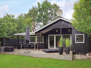 une maison noire avec une terrasse et un parasol dans l'établissement Holiday home Hadsund II, à Hadsund