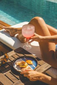 una mujer sentada en una mesa con una bebida junto a una piscina en Casa Luz, en Paraty