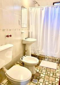 a white bathroom with a toilet and a sink at El Portal de Cerrillos, Hostería de Campo in Cerrillos