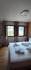 a bedroom with a large white bed with two windows at Primula in Metsovo