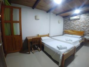 1 dormitorio con 2 camas, escritorio y puerta en Hotel Malibu, en San Juan Nepomuceno