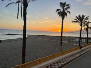 - un coucher de soleil sur la plage avec des palmiers dans l'établissement Primera linea de playa en Torrenueva, à Torrenueva