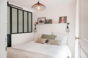 een witte slaapkamer met een bed met witte lakens bij CUTE & COSY 1BDR HOTEL DE VILLE / LE MARAIS in Parijs