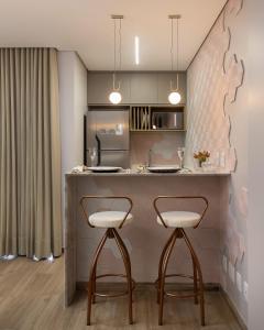 a kitchen with a counter and two stools at a bar at Flat aconchegante in Goiânia