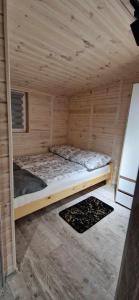 Cabaña de madera con cama en una habitación en Domki Letniskowe RODOS, en Sarbinowo