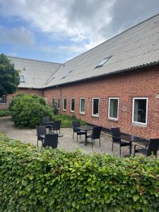 a brick building with tables and chairs in a courtyard at Assersbølgård in Brørup