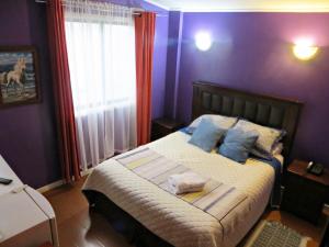 a bedroom with a bed with blue walls and a window at Hostal Remember in Temuco