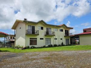 a white house with balconies and a yard at Volcano View Apartment in Fortuna