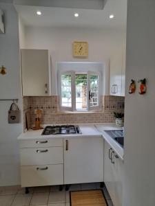 a white kitchen with a stove and a window at La Casa delle sirene sul mare di Anzio in Anzio
