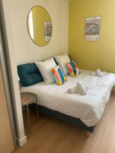 un letto con cuscini e uno specchio in una stanza di Superbe studio centre ville * clim * WIFI * Haut de gamme * ad Angoulême