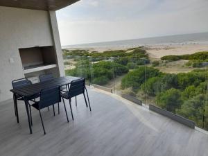 a table and chairs on a balcony with a view of the beach at Northbeach, Pinamar in Costa Esmeralda