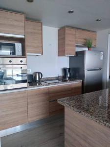 a kitchen with wooden cabinets and a stainless steel refrigerator at Northbeach, Pinamar in Costa Esmeralda