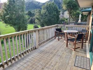 una terraza de madera con sillas y una mesa. en Anakiwa Lodge, en Anakiwa