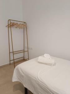 a bed with a white sheet and a metal ladder at SHERRY SUÍTES III apartamentos in Jerez de la Frontera