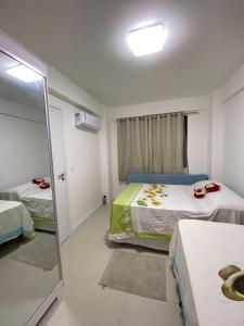 a small room with two beds and a mirror at Apartamento em Guarajuba - Condomínio Paraíso dos Coqueiro in Guarajuba