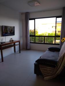 a living room with a couch and a large window at Apartamento em Guarajuba - Condomínio Paraíso dos Coqueiro in Guarajuba