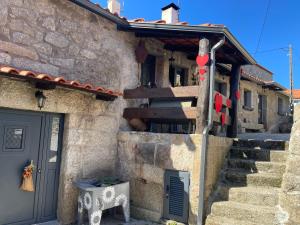 una casa de piedra con una escalera junto a una puerta en O Cantinho da Ana, en Sortelha