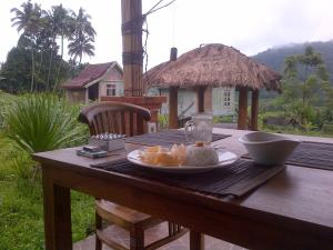 a wooden table with a plate of food on it at Astana Swaha Estate in Sidemen