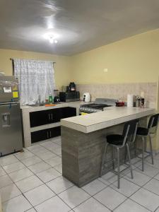 cocina con encimera con 2 sillas y nevera en Mauricio apartment en Monterrey