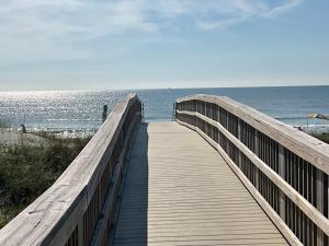 a wooden boardwalk leading to a beach with the ocean at Auberge d'Amelia in Fernandina Beach