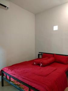 a bedroom with a red bed with a red blanket at Villa Omakost3probolinggo in Probolinggo