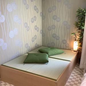Bett mit zwei grünen Kissen auf einem Zimmer in der Unterkunft 遊泊天王寺YupaStay in Osaka