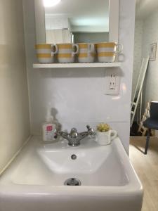 - un lavabo blanc avec des bols sur une étagère au-dessus dans l'établissement 遊泊天王寺YupaStay, à Osaka