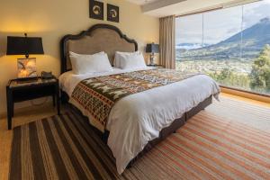a bedroom with a large bed with a large window at Hotel Medina Del Lago in Otavalo