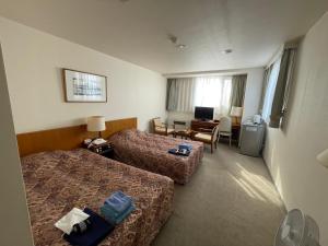 a hotel room with two beds and a desk at Kitaguni Grand Hotel in Rishirifuji
