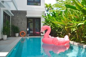 een roze opblaasbare flamingo in een zwembad bij Hoi An Lotus Aroma Villa By HOS in Hội An